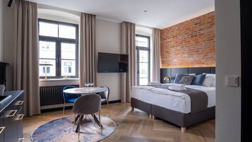 A modern hotel room with a large bed, a desk, and a dining area.