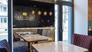 A modern restaurant interior with marble tables, patterned seating, and pendant lighting. - Carvala Boutique Apartments (Czestochowa)