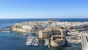 Une ville côtière dotée d’un port fortifié, de bâtiments historiques et d’un ciel d’un bleu limpide.