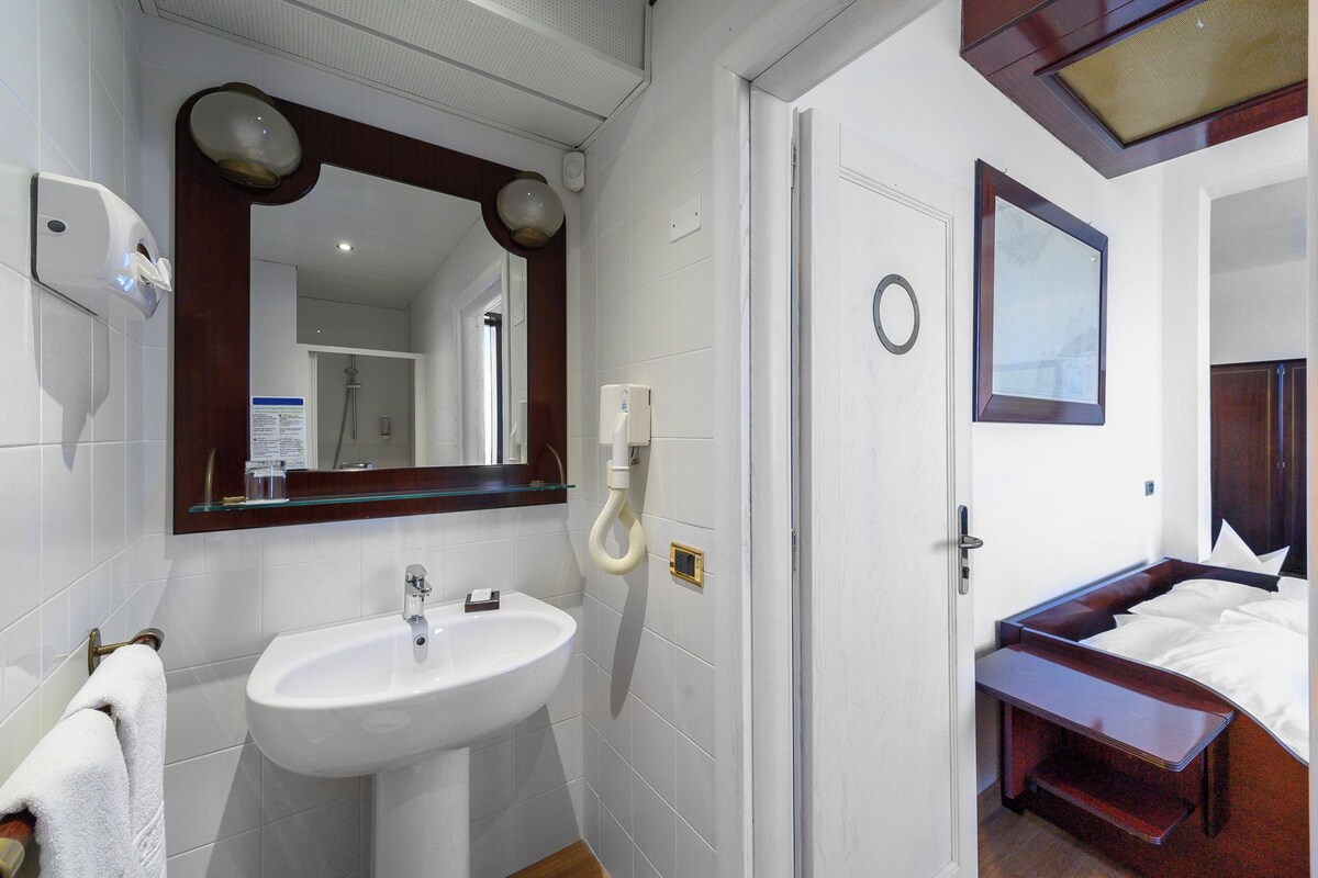 Une salle de bain d’hôtel avec un lavabo, un miroir et une douche.