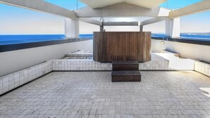 Une terrasse sur le toit offrant une vue sur la mer, un espace salon en bois et un sol carrelé.