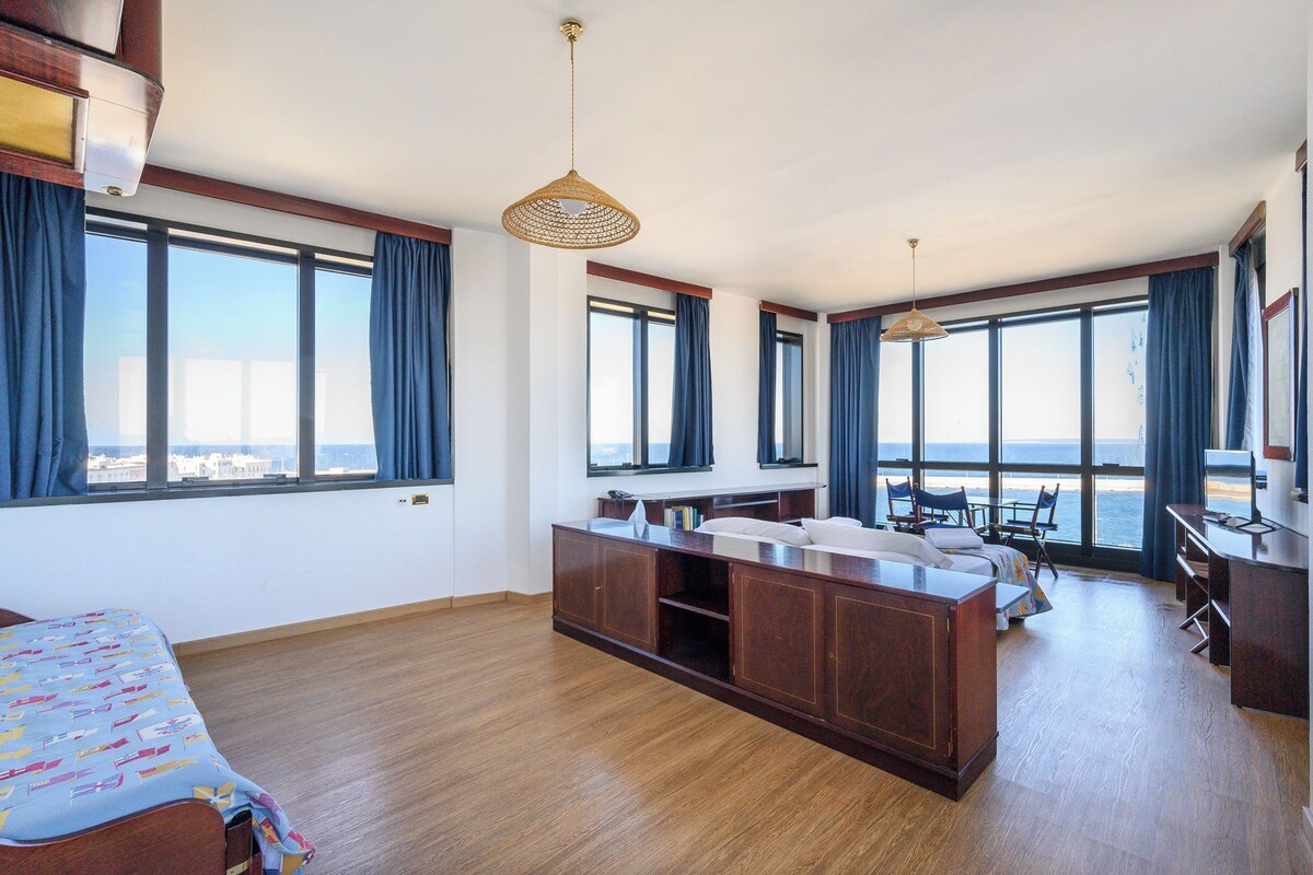 Une chambre d’hôtel spacieuse, dotée d’un grand lit, d’un bureau et offrant une vue sur la mer.