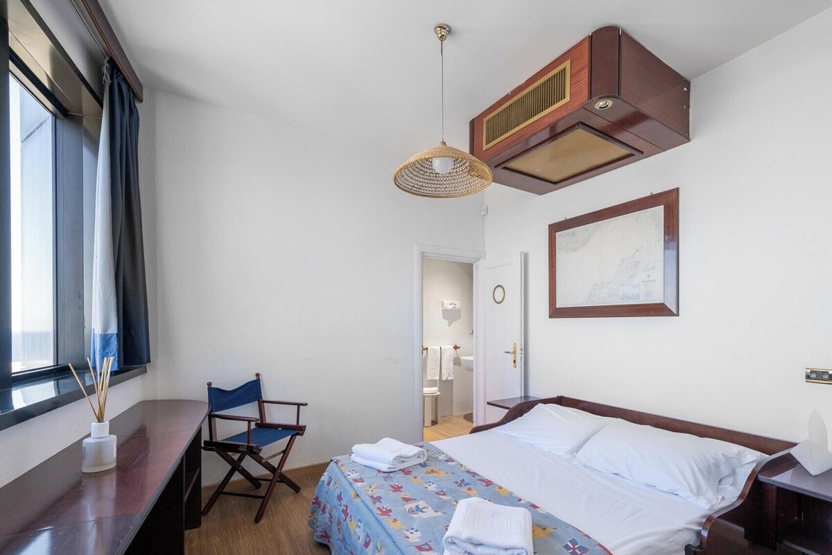Une chambre d’hôtel avec un lit, un bureau, une chaise, une fenêtre et une carte accrochée au mur.