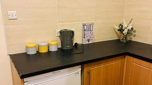 Una cocina con encimera negra, refrigerador blanco, armarios de madera y un letrero que dice 'FAMILY LOVE'.