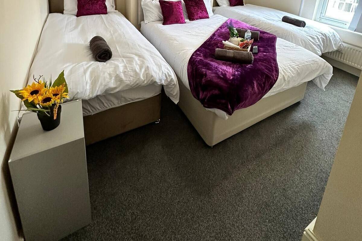 A hotel room with two beds, a flat-screen TV mounted on the wall, and a window providing natural light.