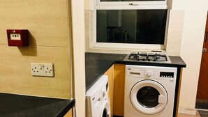 Cocina compacta con lavadora, estufa y una ventana sobre el fregadero.
