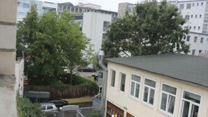 Un edificio residenziale con un balcone visibile, un piccolo giardino con un ombrello rosso e una gru edile vicina.