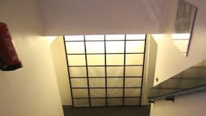 Una scala con corrimano, un estintore a parete e una finestra con grate.