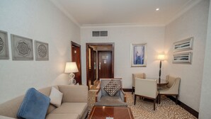 Ein Hotelzimmer mit einer Couch, einem gemusterten Sessel, einem kleinen Tisch und einer Lampe.