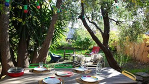Een terras met een houten eettafel, gedekt voor een maaltijd, omringd door stoelen.
