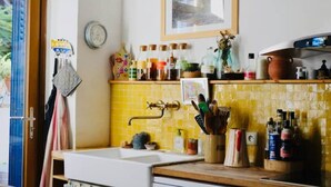 Een keuken met gele tegels, een gootsteen en verschillende keukenspullen op het aanrecht.