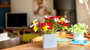Een eettafel met een bloevas en documenten vastgemaakt aan de muur erboven.