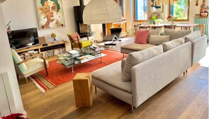 Een moderne woonkamer met een bank, een glazen salontafel, een televisie en een open haard.