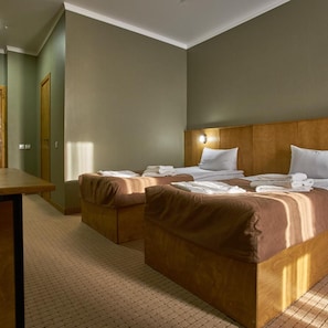 Een hotelkamer met twee bedden, een houten hoofdbord en een klein tafeltje.