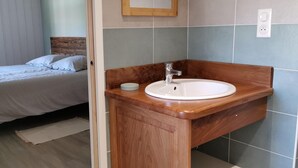 A bedroom with a bed and a wooden vanity with a sink.