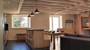 A modern kitchen with wooden cabinets, a dining table, and pendant lighting.