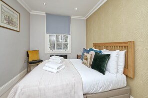 Relax in a cozy retreat with a comfortable bed, a window offering a view, and a chair for unwinding.