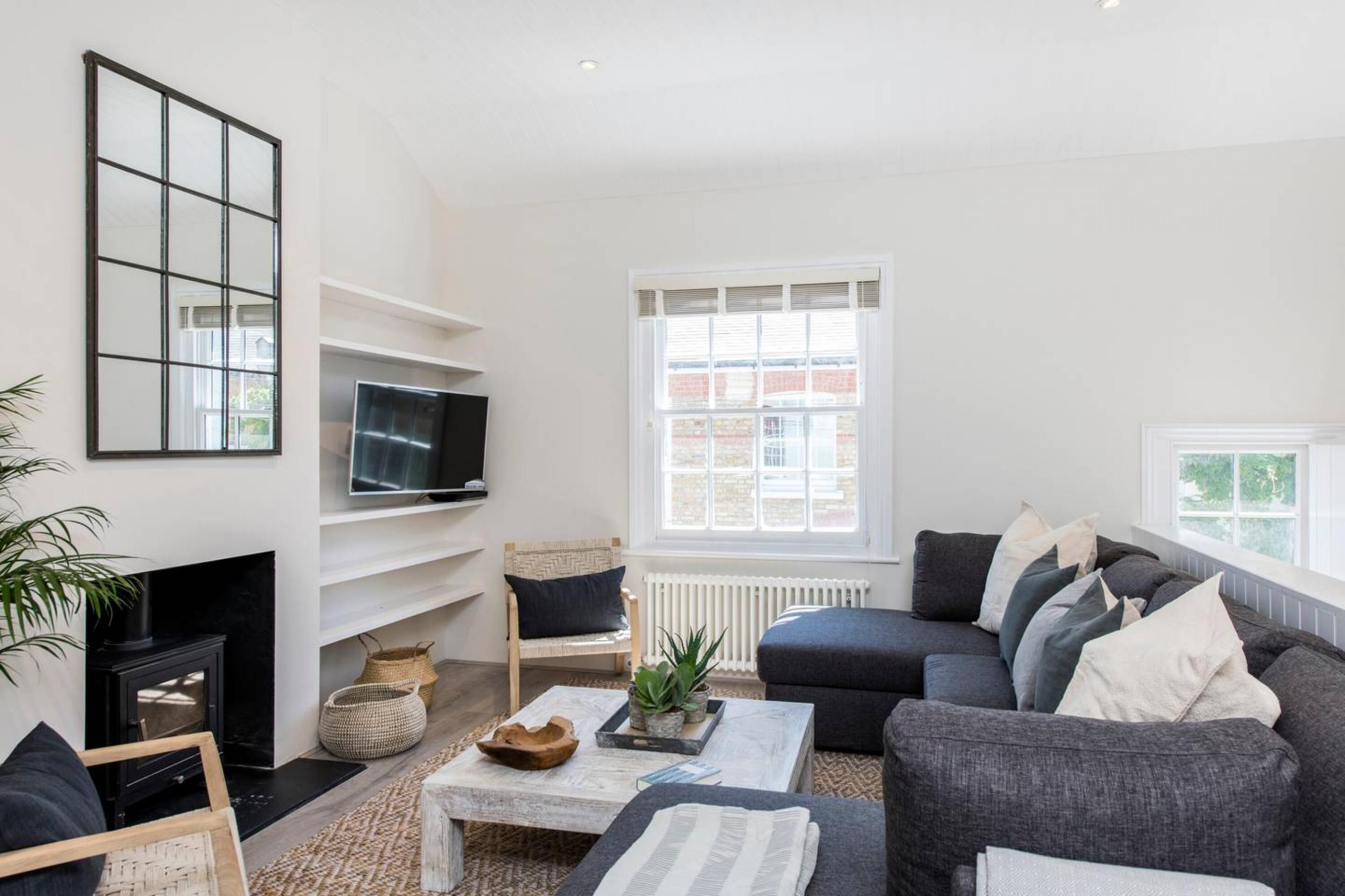 Una sala de estar moderna con chimenea, televisor, sofá y un amplio ventanal.
