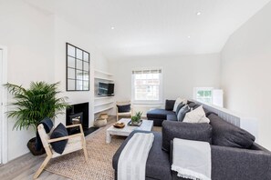 Ein modernes Wohnzimmer mit Kamin, einer Sofagarnitur, einem Couchtisch und einem Fernseher.