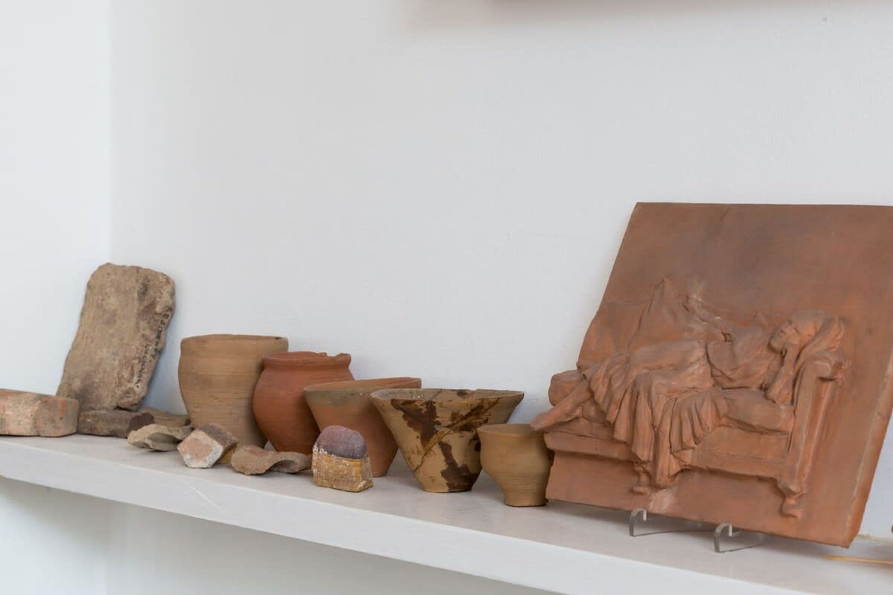 A collection of pottery and sculptures on a white shelf.