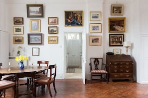A dining room with a wooden table and chairs, surrounded by framed pictures on the walls.