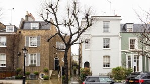Une rangée de maisons mitoyennes avec une voiture noire garée devant.