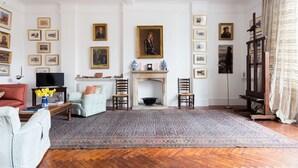 Un salon avec une cheminée, un téléviseur et divers tableaux encadrés accrochés aux murs.