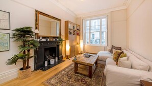 A living room with a fireplace, a sofa, a coffee table, and a large mirror.