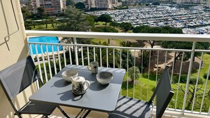 Een balkon met een tafel gedekt voor twee personen, met uitzicht op een jachthaven en woongebouwen.