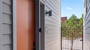 A door with a welcome mat, a mailbox, and a gated driveway. - Spacious Condo in Center of NULU with Free, Gated, Secure Parking and Entrance (Louisville)