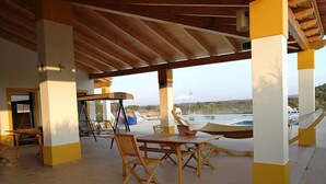 Un patio al aire libre con mobiliario de madera, una hamaca y vistas a un cuerpo de agua.
