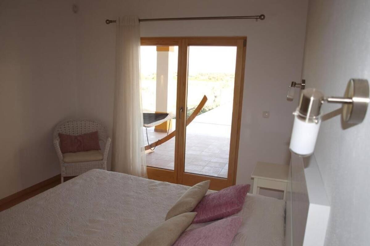 Une chambre à coucher avec un lit, une chaise et une porte coulissante donnant sur un balcon.