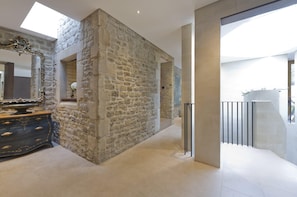 Stunning interior space with a stone wall feature, ornate mirror, and dark dresser.