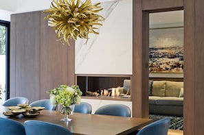 Cozy dining area with a fireplace, wooden paneling, and a large mirror.
