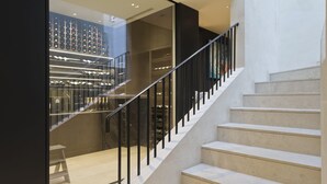 A staircase with a glass enclosure on one side, leading to a second floor. - Stunning 5 bed Fulham Home w Indoor Pool Sauna and Private Garden (London)