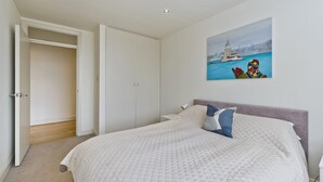 A bedroom with a bed, a nightstand, a painting, and a closet.