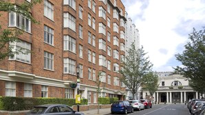 A multi-story brick building with a row of parked cars in front.