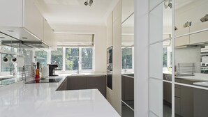 A modern kitchen with a large island, built-in appliances, and large windows providing natural light. - Elegant 2 bed Flat Earls Court (London)