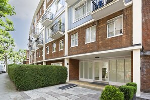 Un immeuble résidentiel à plusieurs étages, doté d’un design moderne, avec des balcons, de grandes fenêtres et une façade bien entretenue.