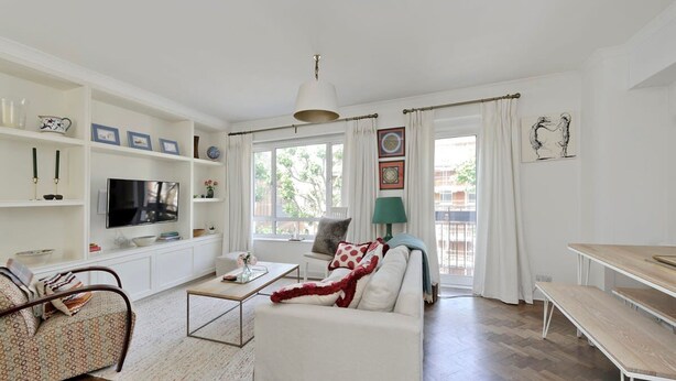 A modern living room with a sofa, coffee table, TV, and a dining area. - Elegant 2 bed Flat Earls Court (London)