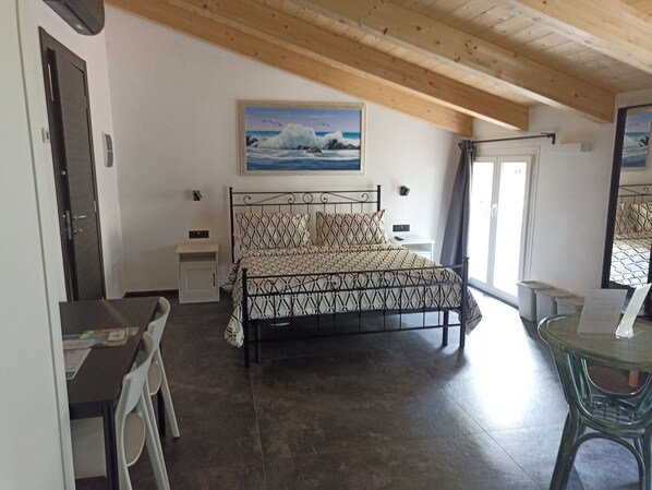 Quarto com cama, escrivaninha, cadeira e mesa de jantar.