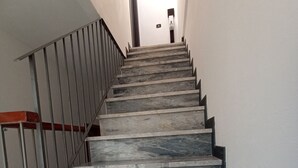 Een marmeren trap met metalen leuningen die uitkomt op een plateau.