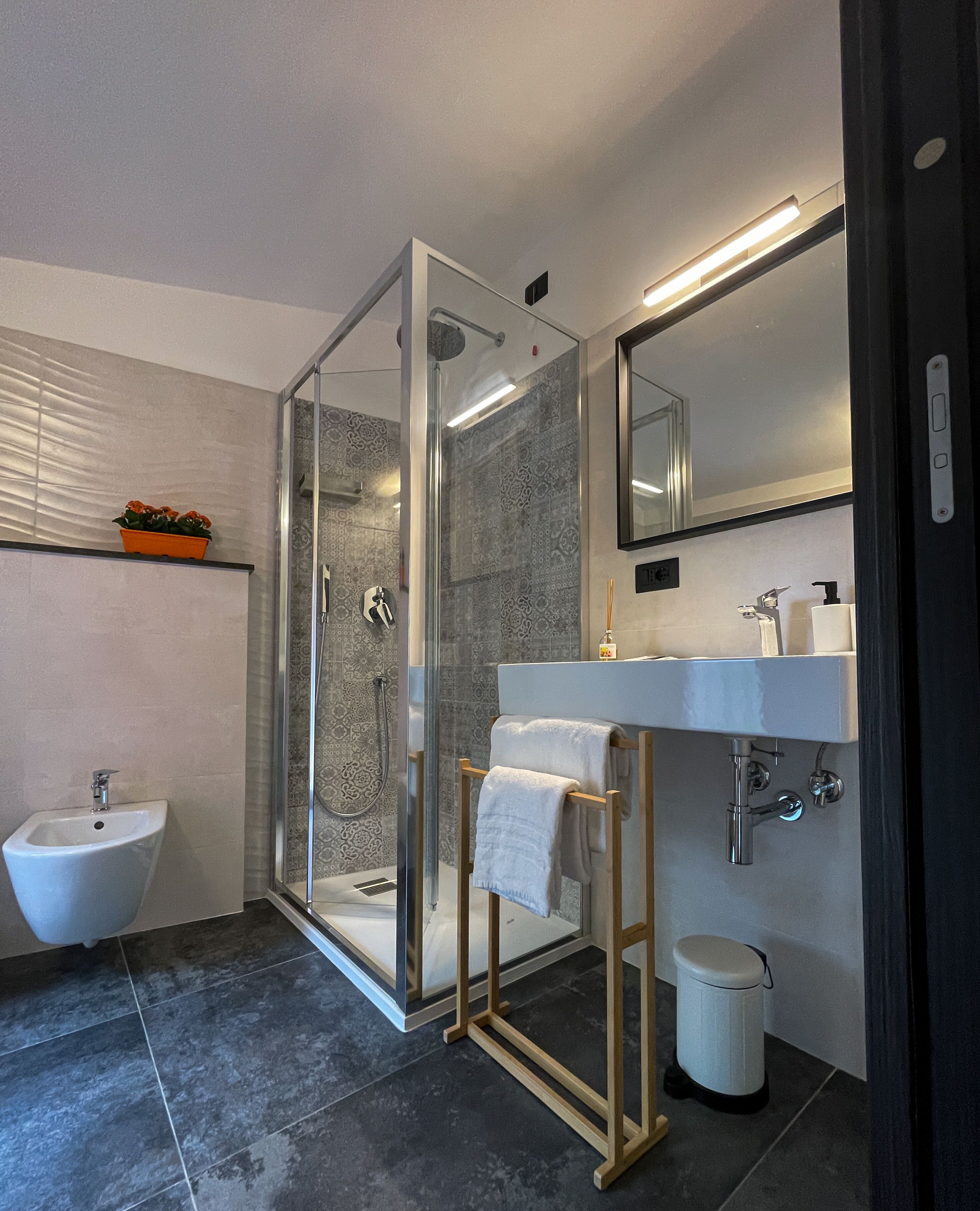 Une salle de bain moderne avec une douche à parois de verre, un lavabo sur colonne et un grand miroir.