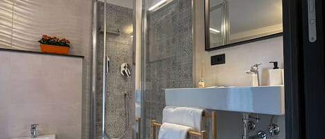 Une salle de bain moderne avec une douche à parois de verre, un lavabo sur colonne et un grand miroir.