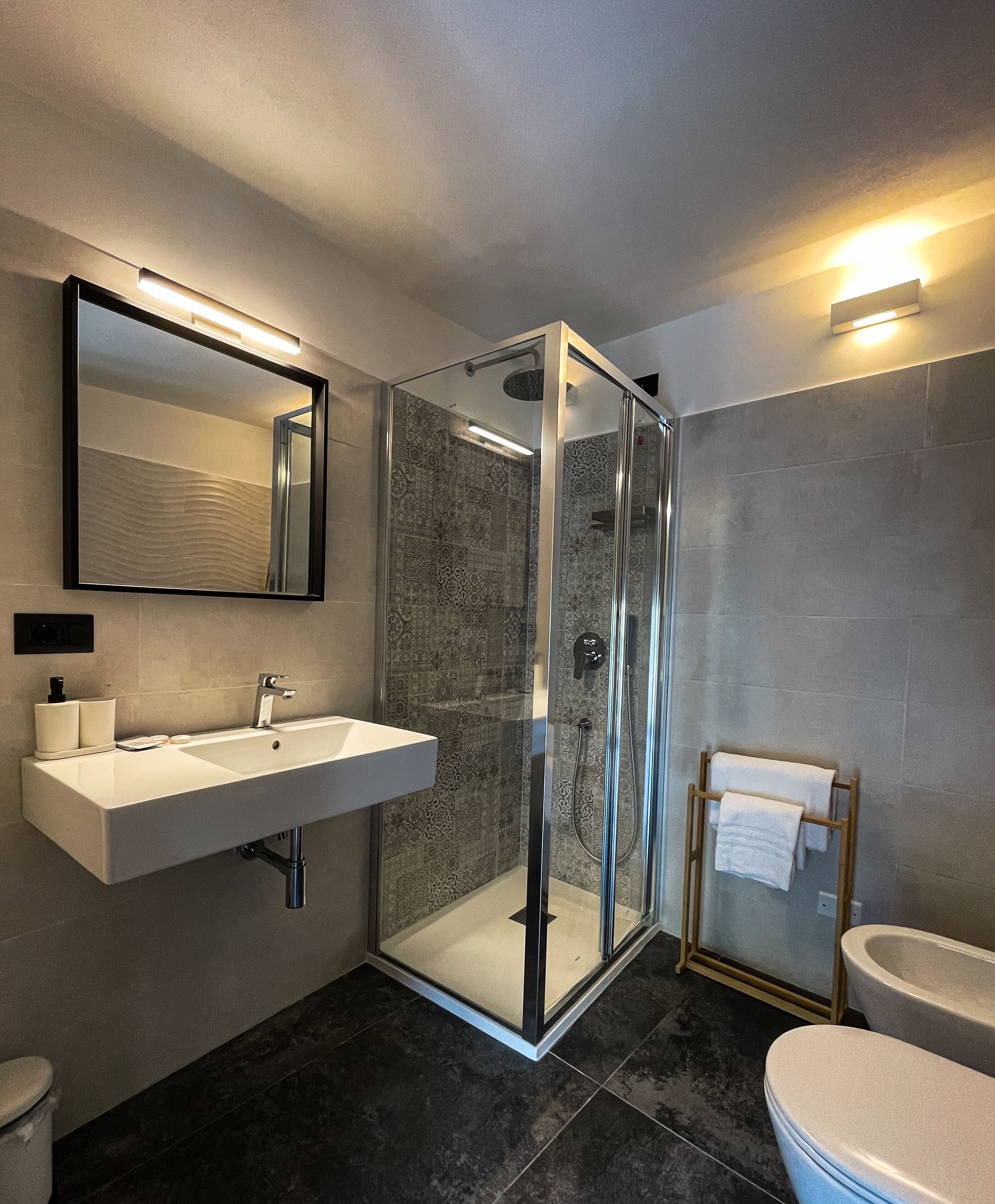 A modern bathroom with a glass-enclosed shower, a sink with a mirror, and a toilet.