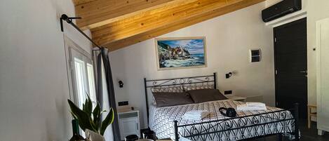 Un dormitorio con una cama, un escritorio con una silla, una ventana, un cuadro en la pared y una puerta.
