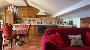 A cozy kitchen with wooden cabinets, a dining table with chairs, and a red sofa with decorative pillows. - Sea View Flat (Giardini Naxos)