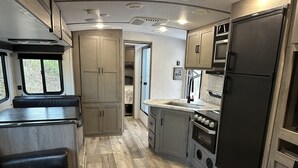 Eine kleine Küchenzeile für ein Wohnmobil mit Spüle, Herd und Schränken.