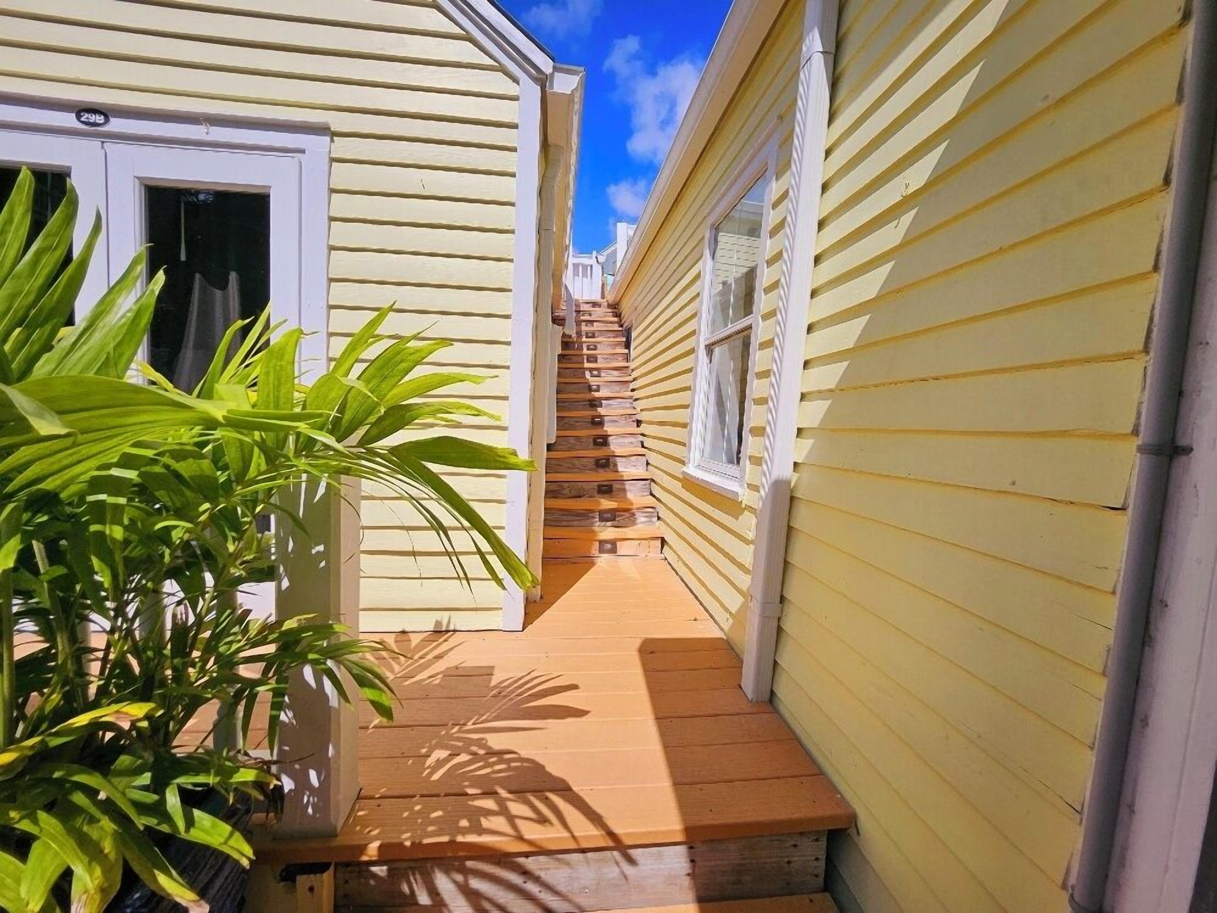 A narrow wooden staircase leading to a door, flanked by yellow siding houses.