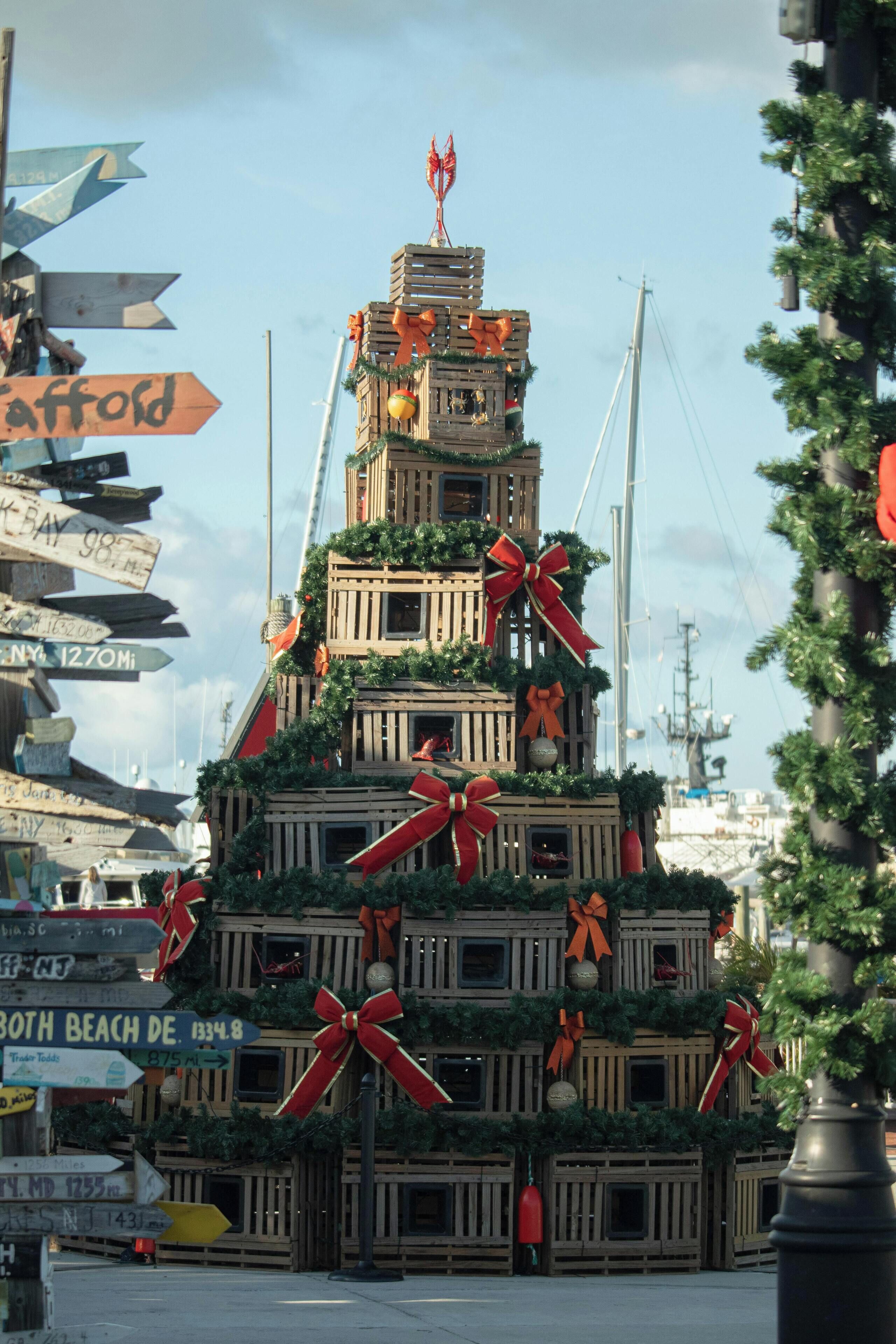 A multi-tiered wooden structure decorated with bows and greenery, resembling a Christmas tree, with directional signs around it.